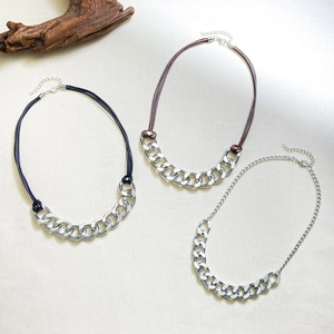 Detailed flat lay of punk style thick Cuban chain necklaces with woven rope accents