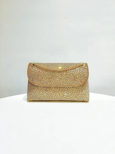 Detailed view of golden evening clutch with swirling rhinestone patterns and chain strap
