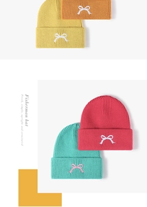 Detail of colorful knitted beanies with embroidered bows in multiple bright colors