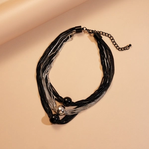 Macro detail of multi-layer metallic chain necklace with black and silver beads