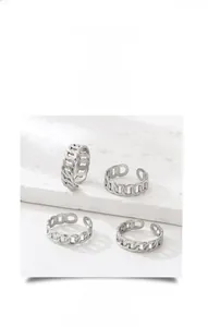 Macro view of four silver Cuban chain adjustable rings on a white stone texture display