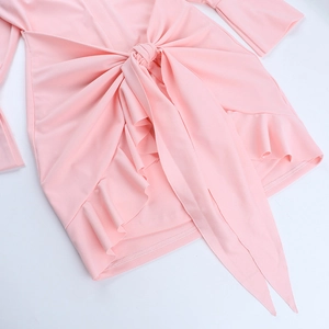 Detail eines rosa Rüschen-Minikleides mit Taillenknoten und Stoffstruktur auf weißem Grund