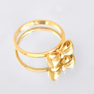 Detail of elegant gold bow ring with polished metallic finish on mirrored background