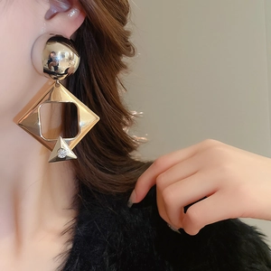 Close-up of a model wearing a large geometric gold earring with sparkling rhinestone detail