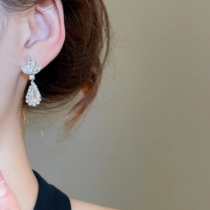 Close-up of model wearing silver wheat-teardrop earrings with sparkling zircons