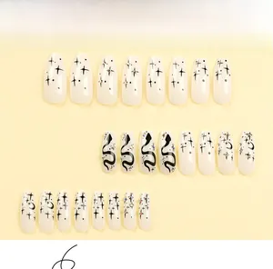 Detail of press-on nails featuring black snake and star patterns with sparkling rhinestones