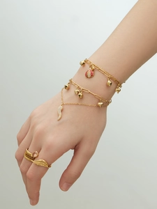 Détail de bracelets superposés dorés avec breloques coccinelle et deux bagues chic