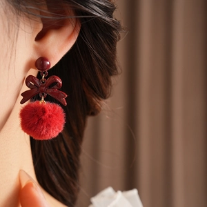 Close-up of wine red bow knot earrings with soft plush fur balls on model