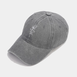Detail of white faith embroidery and dandelion design on gray washed cotton cap