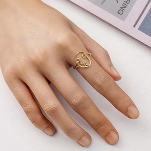 Detail of gold hollow abstract face ring showing artistic line design on fingers