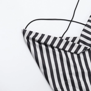 Detail dünner schwarzer Träger an einem gestreiften rückenfreien Kleid mit Glanzeffekt