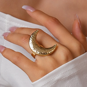 Close-up of a gold moon-shaped adjustable ring with hammered texture worn on a finger