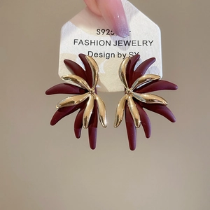 Detailed macro of vintage flower stud earrings in burgundy matte and gold finish