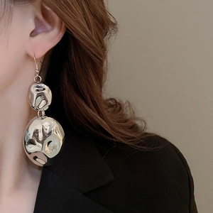 Detail of silver drop earrings with hammered texture and molten metal design for women