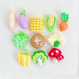 Flat lay of 11 miniature resin charms including corn, carrot, broccoli and eggplants