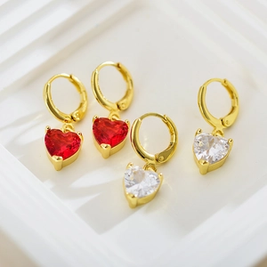 Macro shot of gold hoop earrings featuring vibrant red and clear heart-shaped zircons