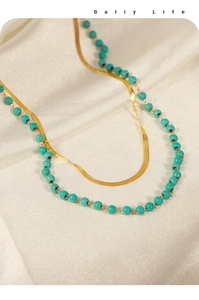 Detail of double-layer necklace with golden herringbone chain and turquoise beads