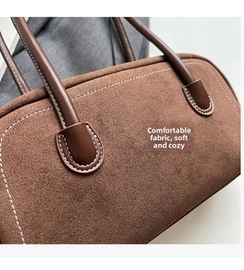 Detail of dark brown faux suede shoulder bag featuring fine contrast stitching and leather handle