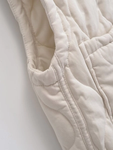 Detailed close-up showing the premium quilted texture and armhole stitching of the beige vest