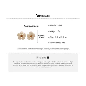 Detail showing white beaded camellia flower earrings with gold core and silver needles