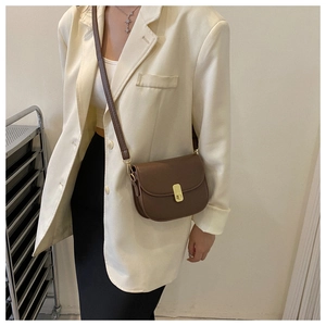 Brown leather saddle bag with gold buckle worn on shoulder to show size and fit