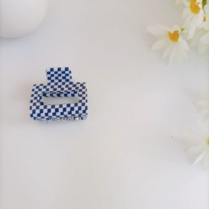 Detail of blue checkerboard acrylic hair claw clip with white daisy decoration