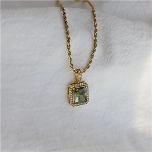 Macro shot of gold twist chain necklace with rectangular green gemstone pendant and diamonds