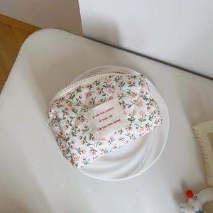 Macro shot of pink floral quilted cosmetic bag with French slogan label in a ceramic dish