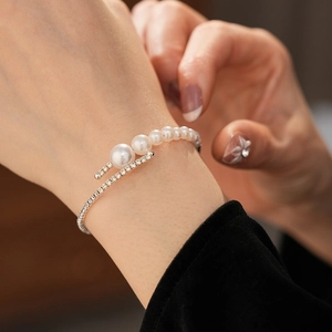 Detail of silver open bangle with gradient white pearls and sparkling diamond accents