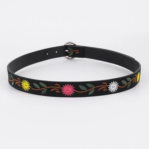 Close-up of floral embroidery on black waist belt with a round metallic buckle