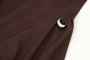 Close-up of the silver crescent metal buckle and pleated brown twill fabric on dress side