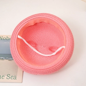 Détail de l'intérieur d'un chapeau de paille rose avec bandeau et cordon élastique