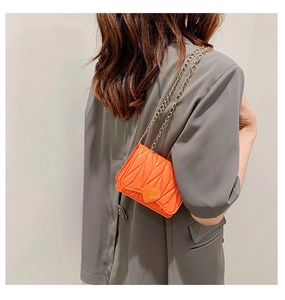 Detailed back view of a bright orange heart-shaped clasp chain bag on a grey coat