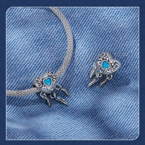 Macro shot of silver heart dreamcatcher charm with blue gemstone and feathers on denim