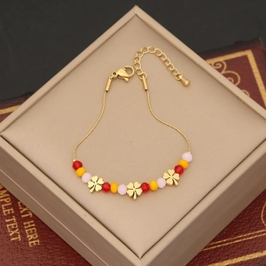 Détail d'un bracelet doré avec trèfles et perles multicolores dans son écrin cadeau