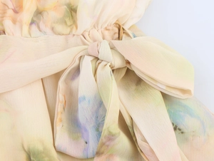 Dettaglio del fiocco in vita sul vestito in chiffon giallo chiaro a fiori acquerello