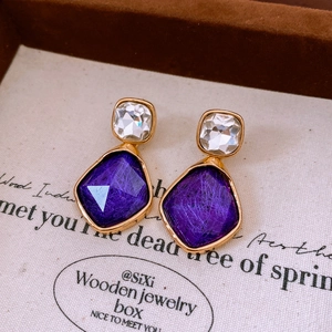Macro shot of vintage style geometric earrings with purple resin stones and gold trim