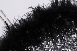 Détail macro de robe à paillettes avec plumes noires et bretelles en strass brillants