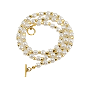 Collier de perles rétro avec billes dorées et fermoir OT sur un fond blanc épuré