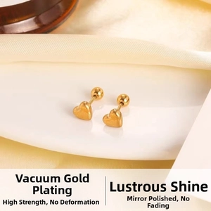 Macro shot of 18K gold-plated heart stud earrings with polished mirror surface on silk fabric