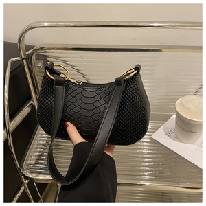 Close-up of black crocodile pattern faux leather handbag with gold metal hardware details