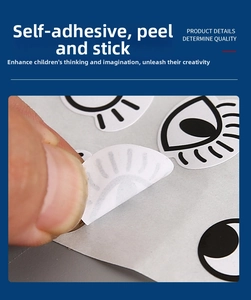 Close-up of hand peeling a cartoon eye sticker showing the adhesive backing for DIY crafts