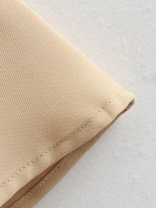 Détail de la texture en sergé beige et des coutures précises sur la robe longue sans manches