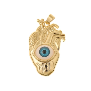 Macro shot of gold heart pendant with detailed textures and a blue evil eye stone