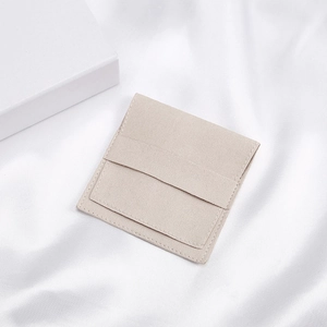 Beige velvet envelope jewelry pouch with a white gift box on white satin background