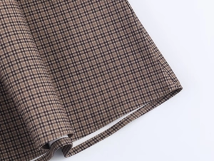 Macro close-up showing brown checkered fabric texture and fine stitching detail of the dress