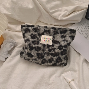 Detailed view of leopard print plush cosmetic bag on white fabric background