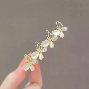 Close-up of golden hair clip with four butterfly shapes, white pearls and small diamonds