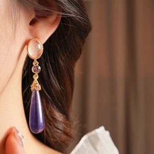 Gros plan de boucles d'oreilles vintage en résine avec gouttes violettes sur un mannequin