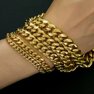Close-up of gold plated Cuban link necklaces worn on wrist with metallic luster
